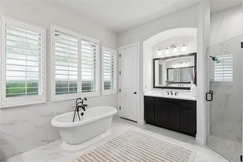 a spacious bathroom with a bathtub double sink and mirror