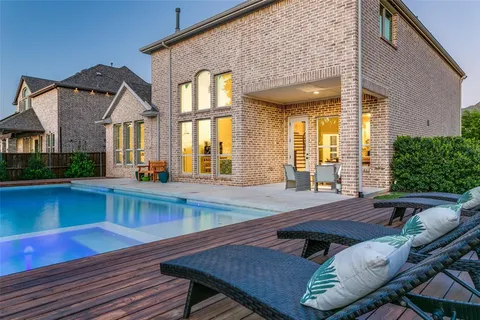 a view of a house with pool chairs and wooden floor