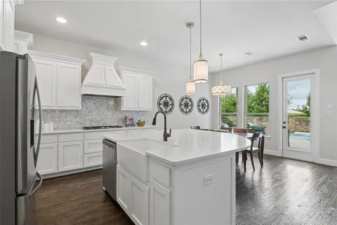 a kitchen with kitchen island granite countertop a sink a stove and chairs