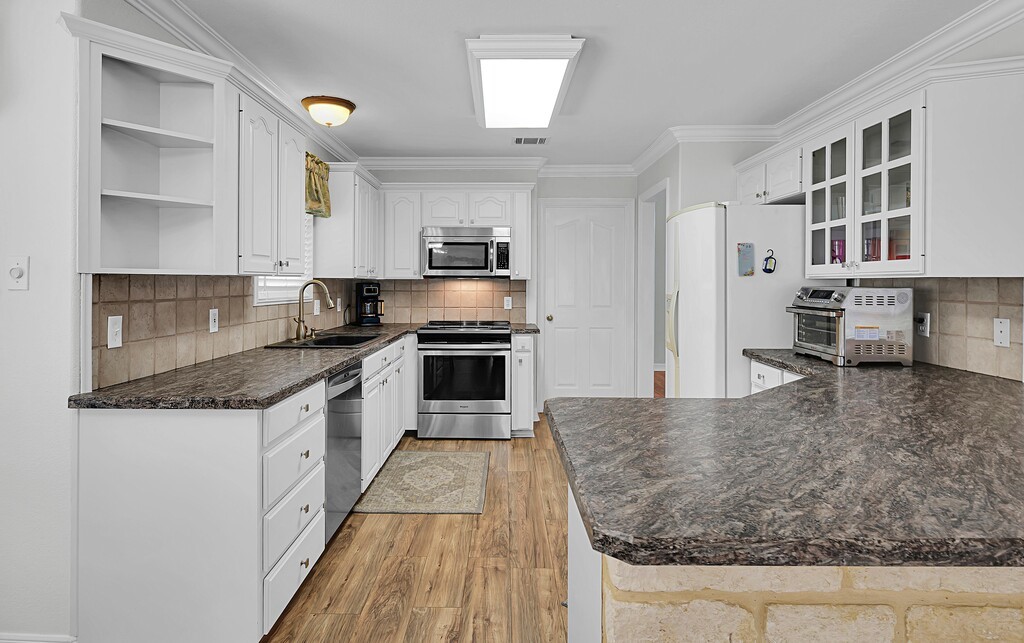 621 South Ruidoso Downs Drive Robinson, TX 76706 - Photo 10 of 41 a large kitchen with granite countertop a sink and dishwasher a stove top oven with wooden floor