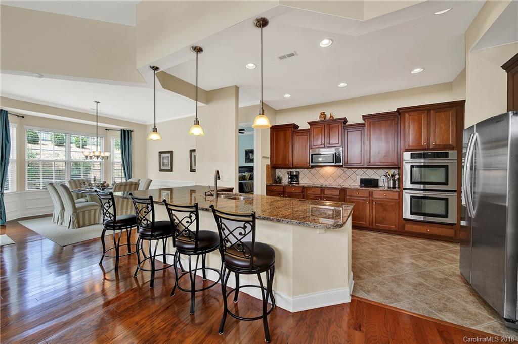 1336 Secret Path Drive Fort Mill, SC 29708 - Photo 6 of 27 a kitchen with stainless steel appliances granite countertop wooden floor a stove a refrigerator a kitchen island a dining table and chairs