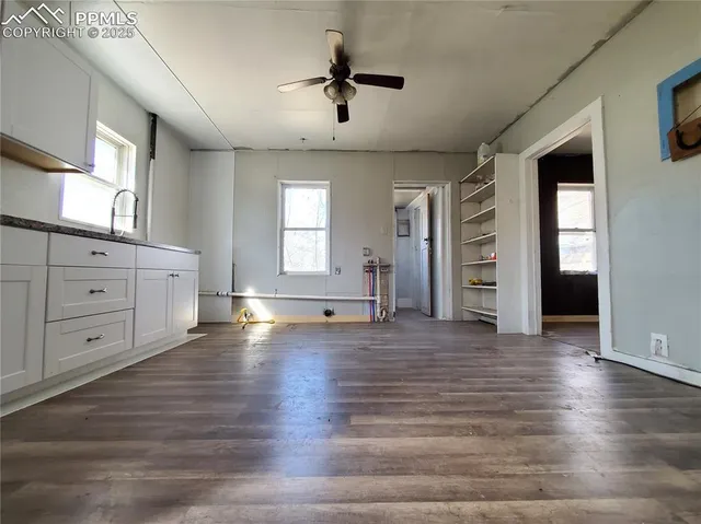 a view of an empty room with a window and wooden floor