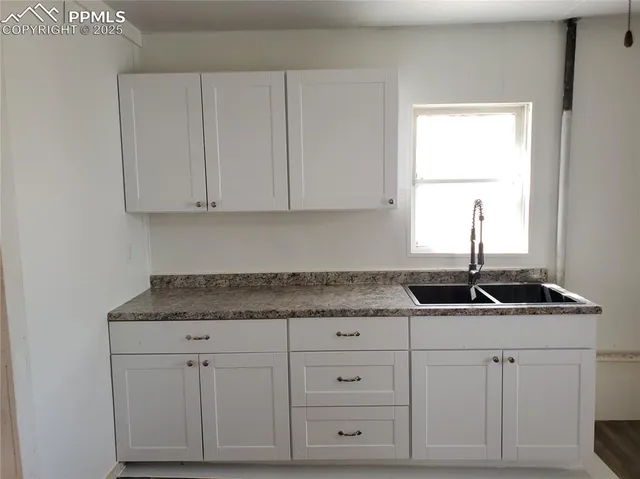 a kitchen with granite countertop white cabinets and a sink