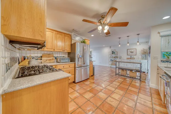 a kitchen with stainless steel appliances a stove a refrigerator a sink a dining table and chairs with wooden floor