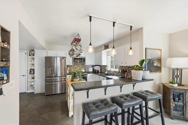 a dinning room with stainless steel appliances kitchen island granite countertop furniture and a kitchen view