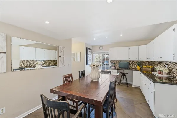 a kitchen with a dining table chairs and white cabinets