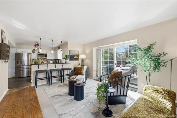 a living room with furniture a potted plant and a kitchen view