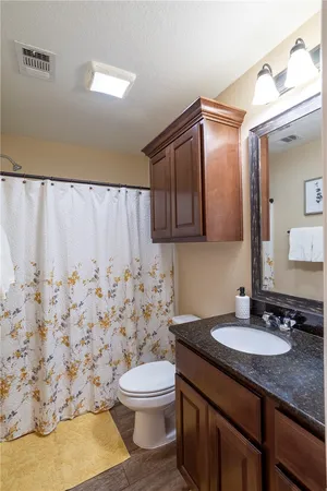 a bathroom with a granite countertop sink and a toilet