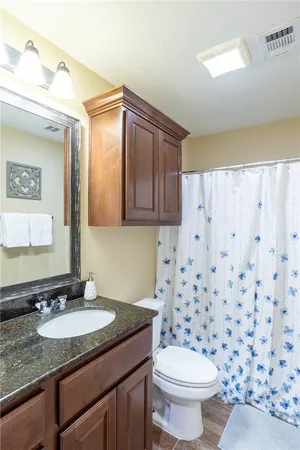 a bathroom with a granite countertop sink a toilet and a mirror