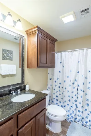 a bathroom with a granite countertop sink a toilet and a mirror