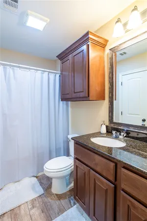 a bathroom with a granite countertop sink toilet and mirror