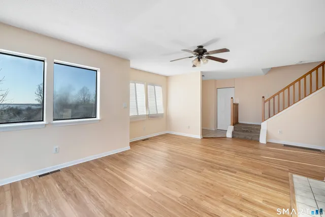 a view of an empty room with a window and wooden floor