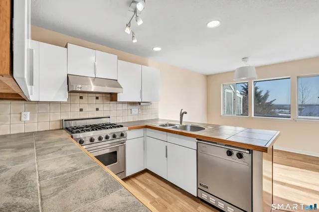 a kitchen with granite countertop a sink stainless steel appliances and cabinets