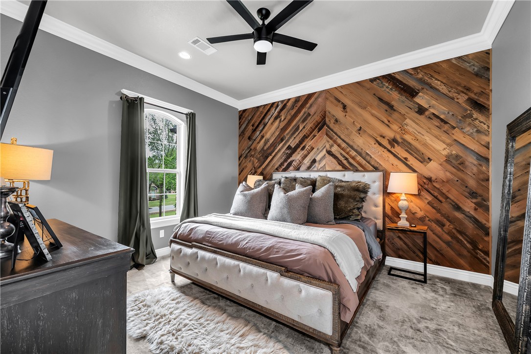 3510 Copper Ridge Road Rogers, AR 72756 - Photo 27 of 58 This bedroom features a striking wood accent wall with a chevron pattern, a ceiling fan, and crown molding