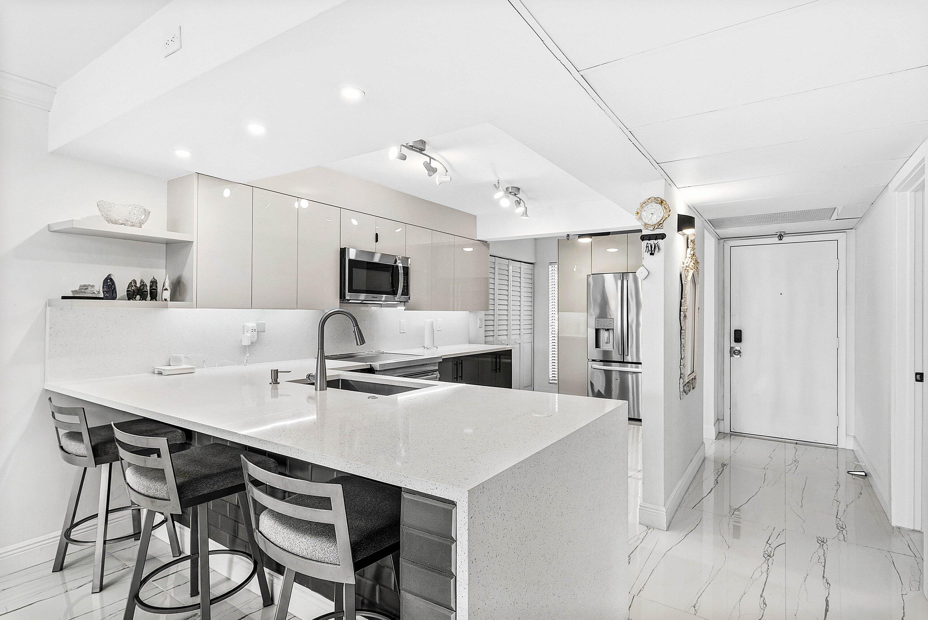 18 Royal Palm Way, Unit 109 Boca Raton, FL 33432 - Photo 8 of 43 a kitchen with kitchen island a stove a table and chairs in it