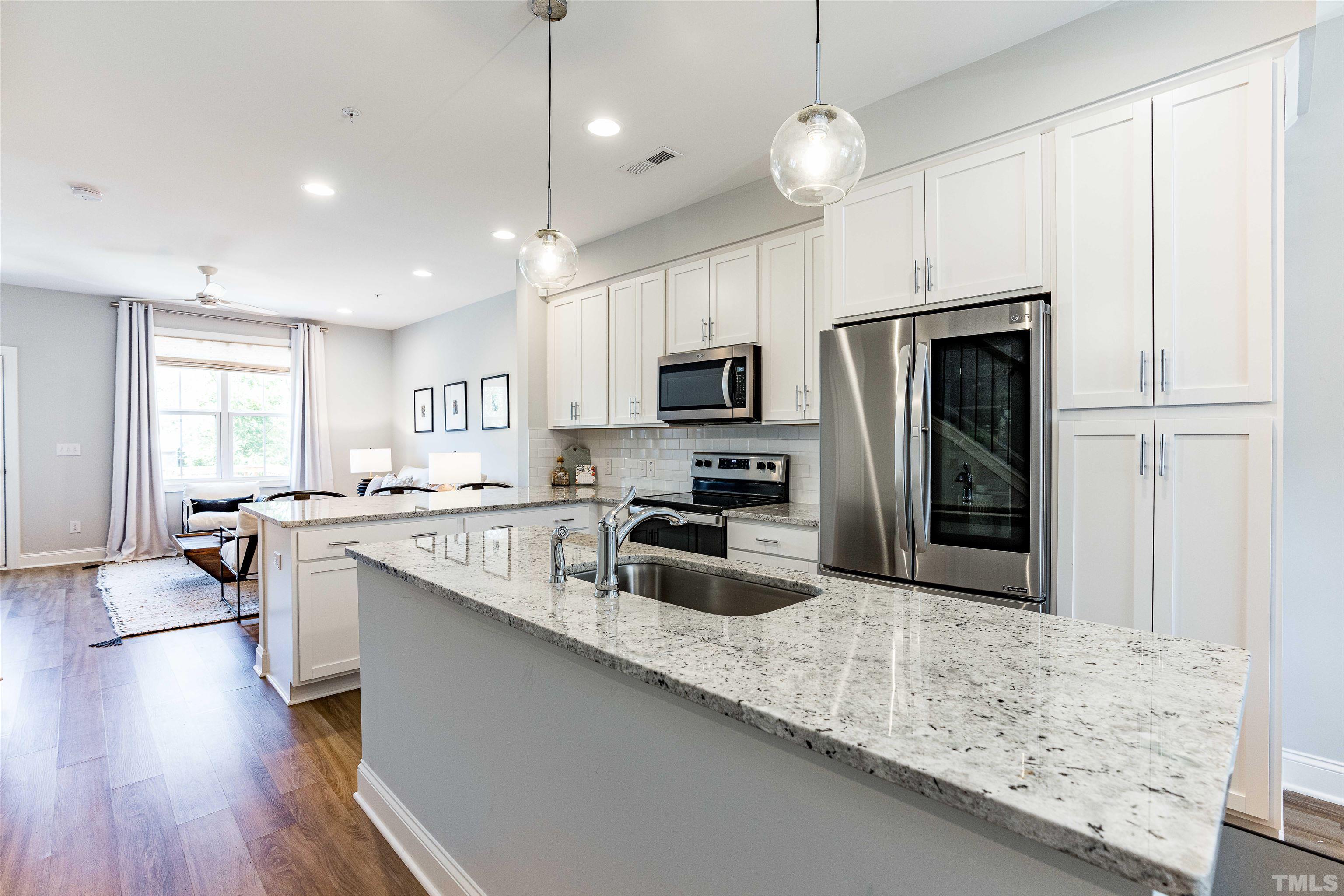6801 Milligan Way, Unit 107 Raleigh, NC 27613 - Photo 3 of 27 a kitchen with stainless steel appliances granite countertop a sink refrigerator and microwave