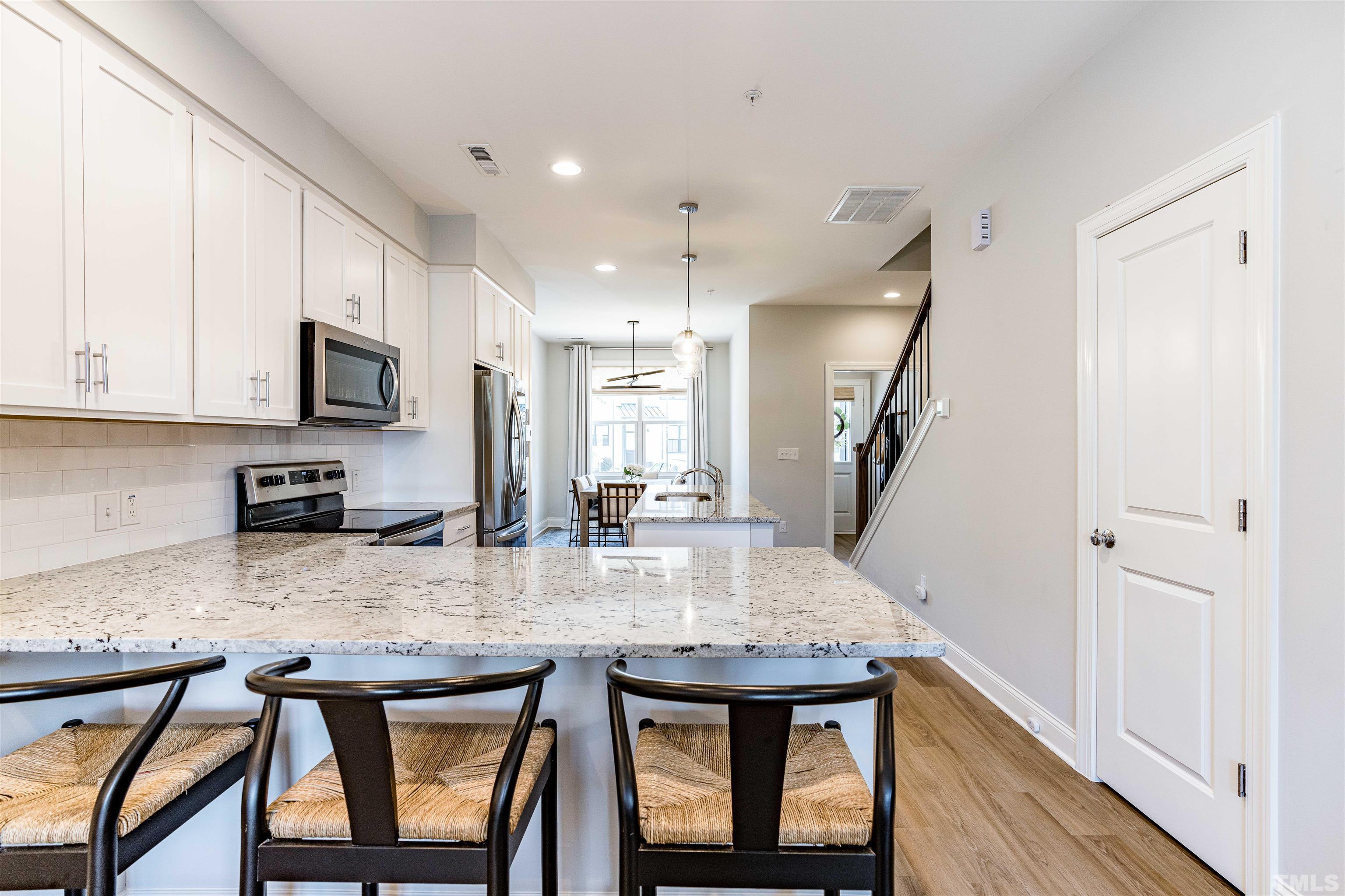 6801 Milligan Way, Unit 107 Raleigh, NC 27613 - Photo 6 of 27 a kitchen with kitchen island granite countertop a stove a sink and a refrigerator with wooden floor