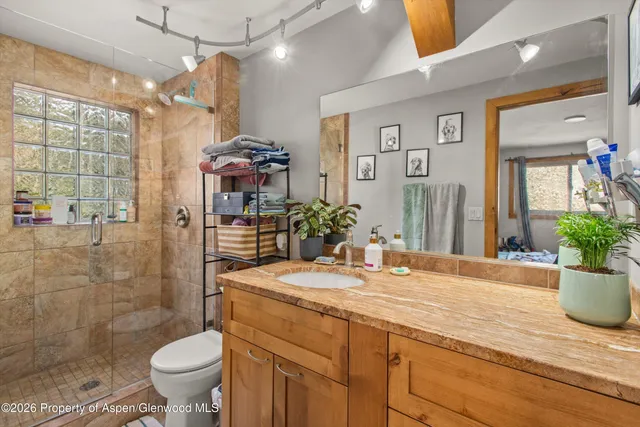 a bathroom with a granite countertop sink a toilet a mirror and shower