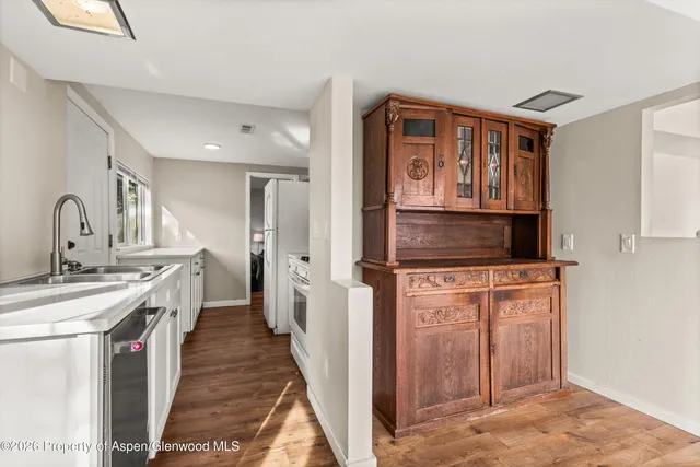 a kitchen with stainless steel appliances granite countertop a stove top oven a sink dishwasher and a refrigerator with wooden floor