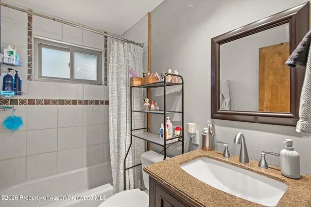a bathroom with a granite countertop sink a toilet and shower