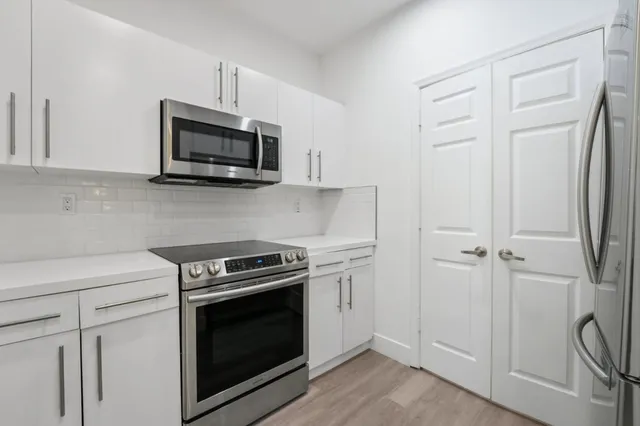 a kitchen with white cabinets and stainless steel appliances