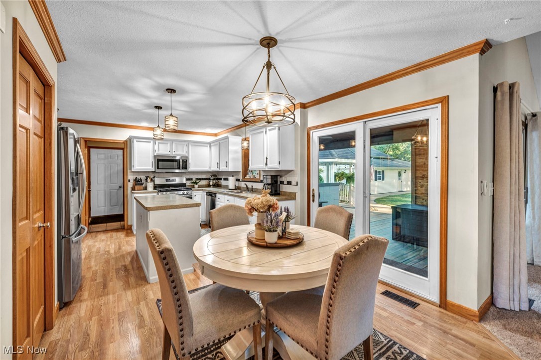 14902 Kneisel Road Vermilion, OH 44089 - Photo 15 of 49 Dining room featuring an inviting chandelier, a textured ceiling, light hardwood / wood-style flooring, and crown molding