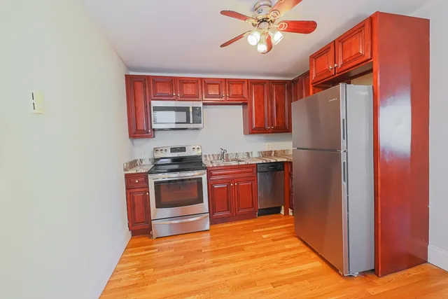 a kitchen with stainless steel appliances granite countertop a refrigerator a stove top oven a sink and dishwasher with wooden floor