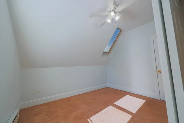 an empty room with a ceiling fan and carpet