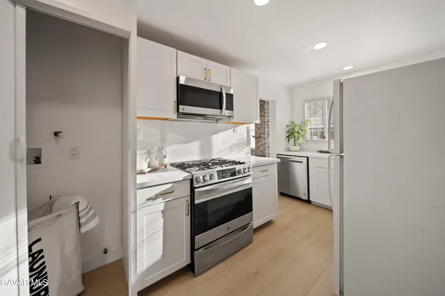a kitchen with stainless steel appliances white cabinets a sink and a stove