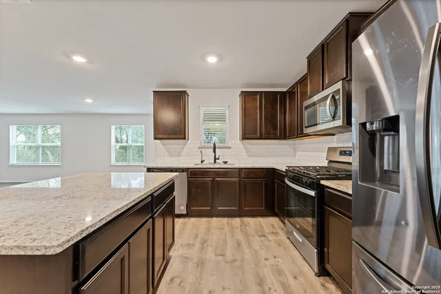 a kitchen with stainless steel appliances granite countertop a sink stove and refrigerator