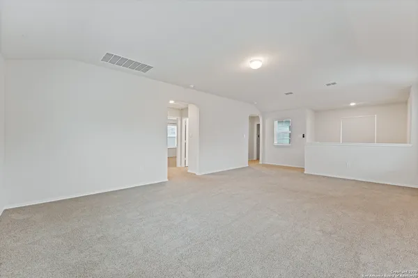 a view of an empty room and a kitchen