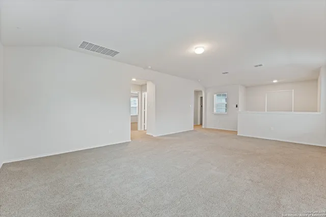 a view of an empty room and a kitchen