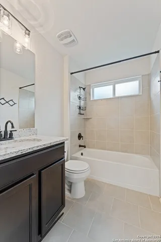 a bathroom with a granite countertop sink a toilet and shower