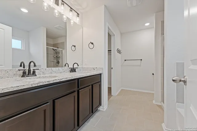 a bathroom with a granite countertop sink two mirror and shower