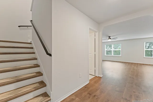 a view of an empty room with wooden floor and windows