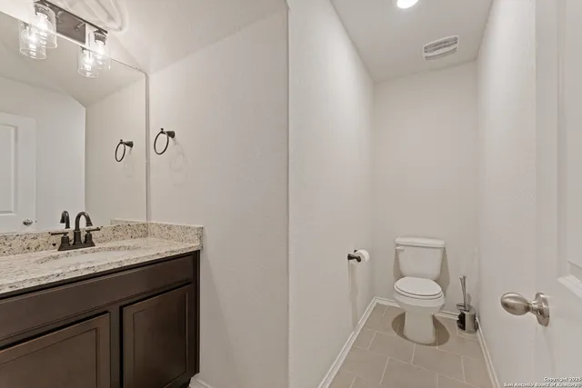 a bathroom with a granite countertop sink toilet and mirror