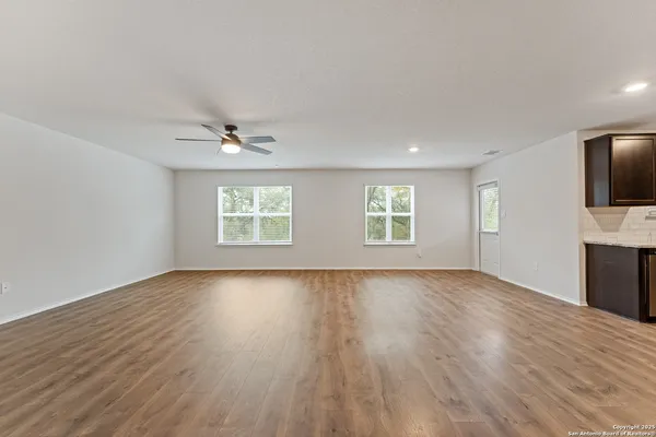 a view of an empty room with a window and wooden floor