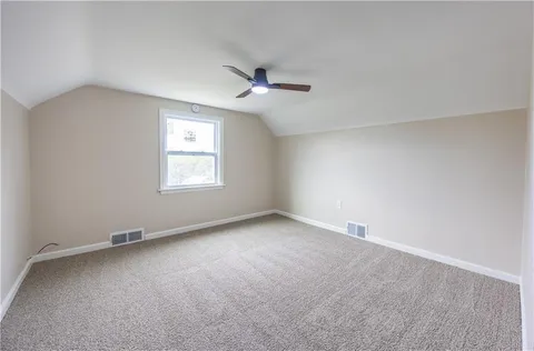an empty room with a window and ceiling fan