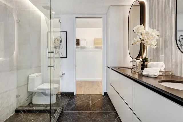 a bathroom with a double vanity sink a toilet and a mirror