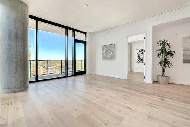 a living room with stainless steel appliances wooden floor and a large window