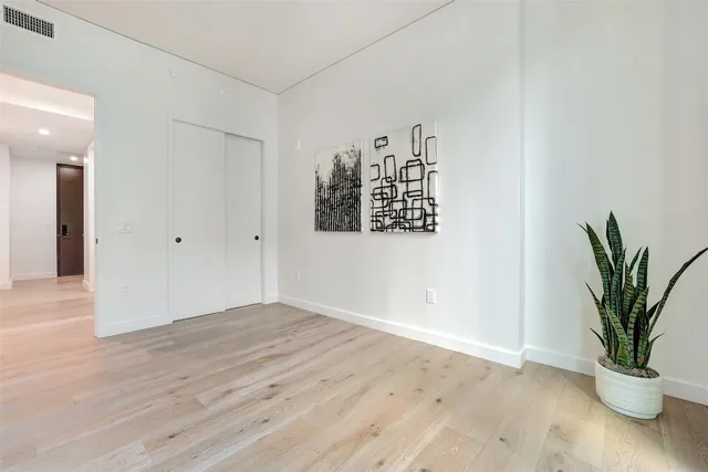 an empty room with wooden floor and a potted plant