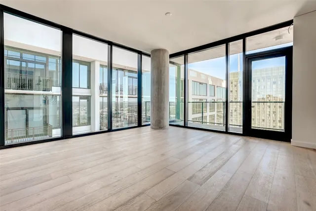 a view of an empty room with window and wooden floor
