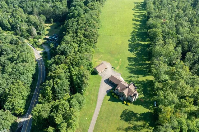 an aerial view of residential house with outdoor space and trees all around