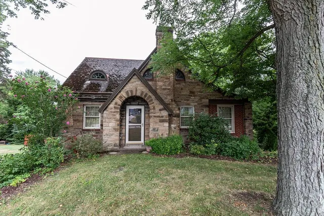 a view of a house with a small yard plants and large tree