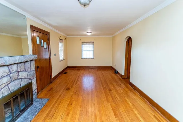 a view of an empty room with wooden floor fireplace and a window