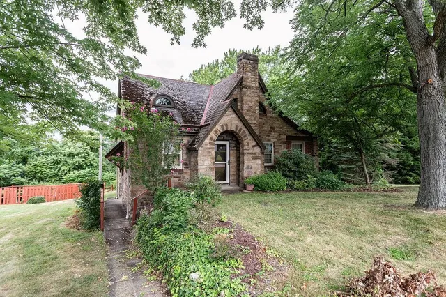 a view of a house with a small yard plants and large tree