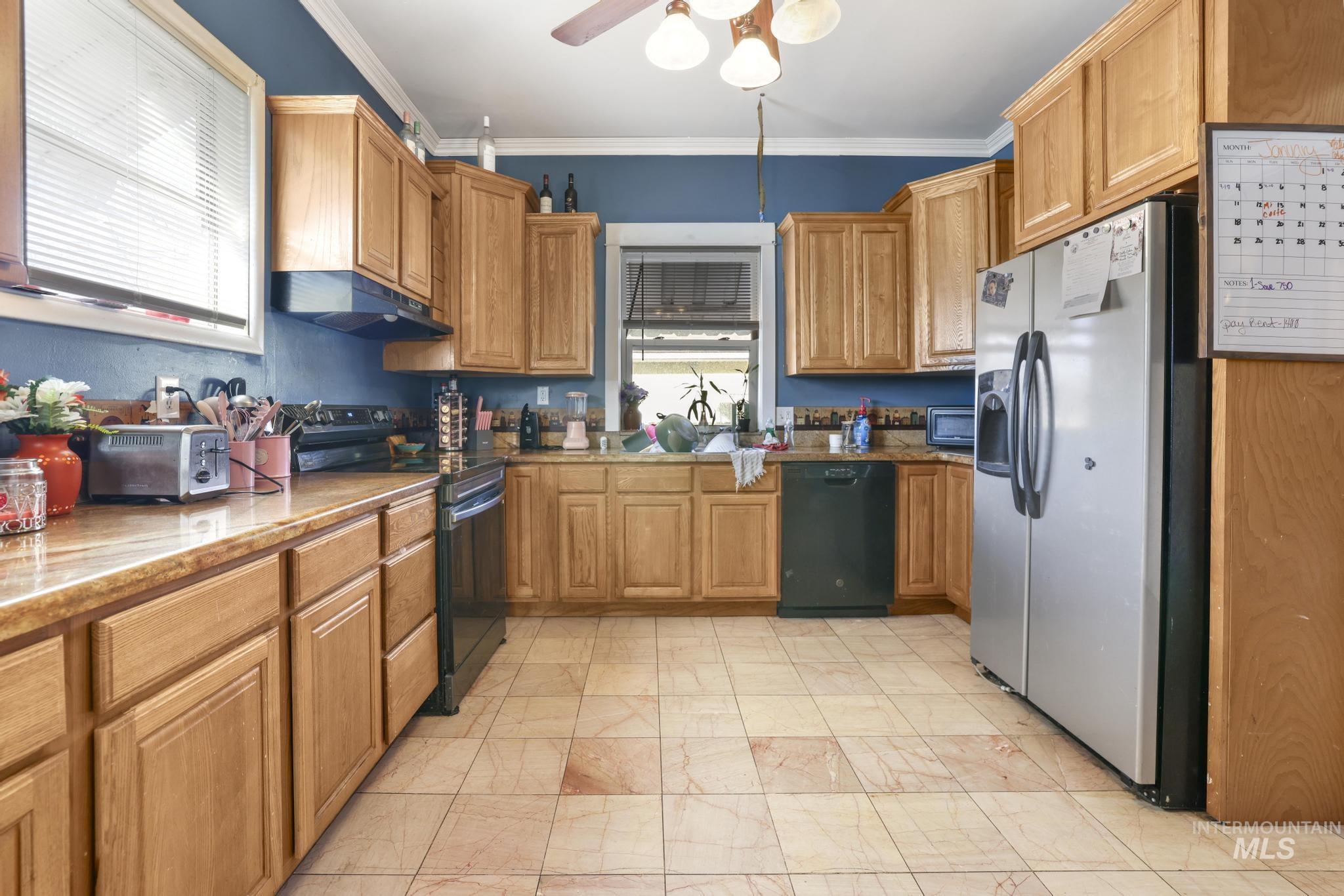 242 8th Avenue East Twin Falls, ID 83301 - Photo 11 of 35 Kitchen with black appliances, ornamental molding, brown cabinets, under cabinet range hood, and light stone counters