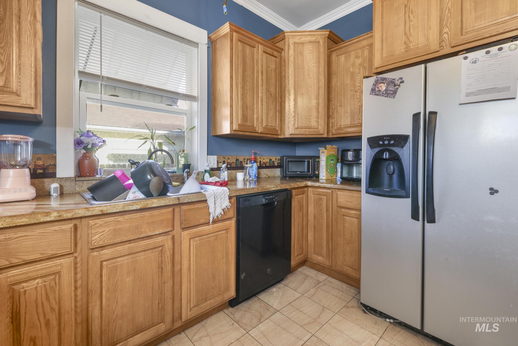 242 8th Avenue East Twin Falls, ID 83301 - Photo 12 of 35 Kitchen featuring stainless steel fridge with ice dispenser, black dishwasher, ornamental molding, brown cabinetry, and light stone counters