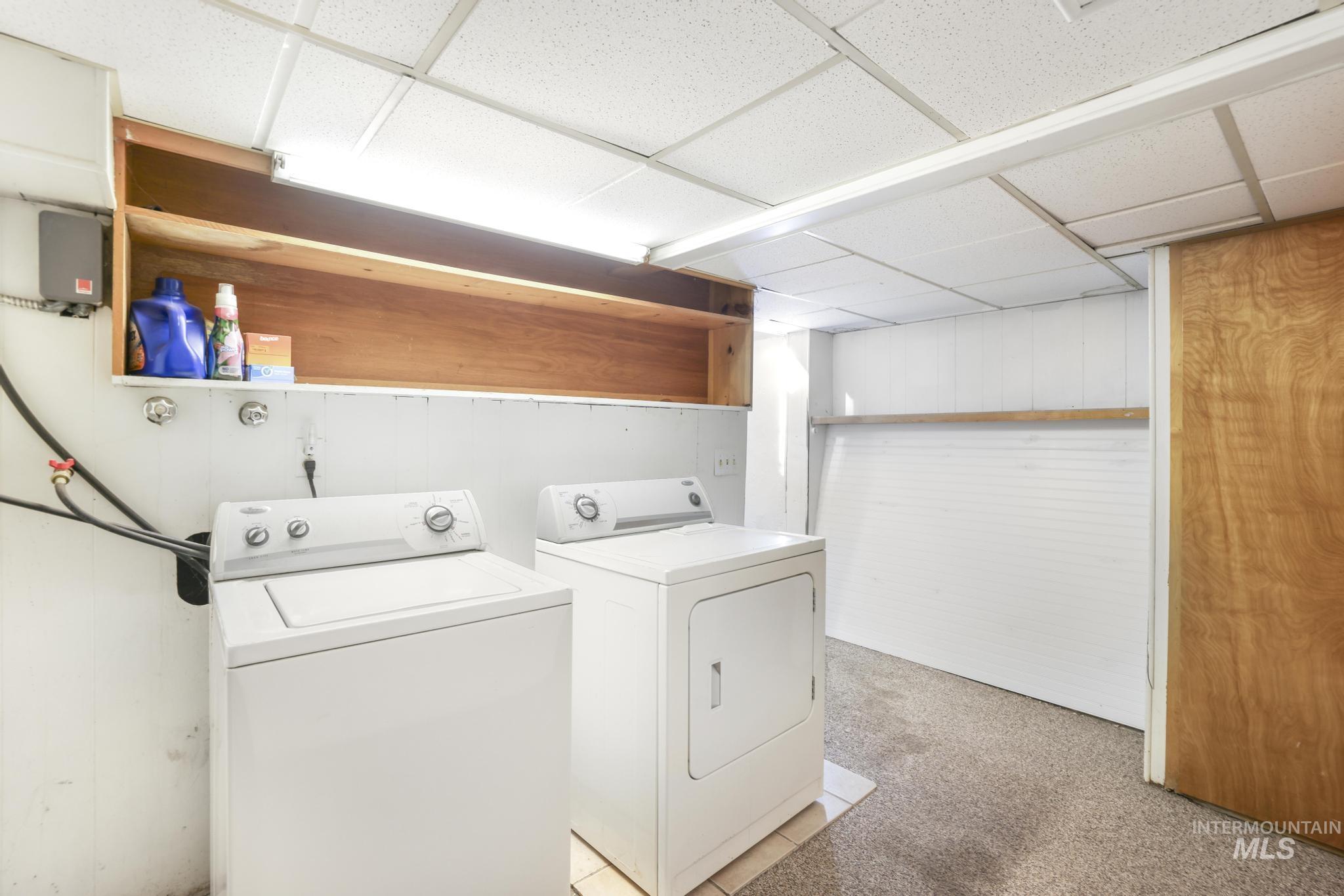 242 8th Avenue East Twin Falls, ID 83301 - Photo 23 of 35 Laundry area with washing machine and clothes dryer, light carpet, a drop ceiling, and wood walls