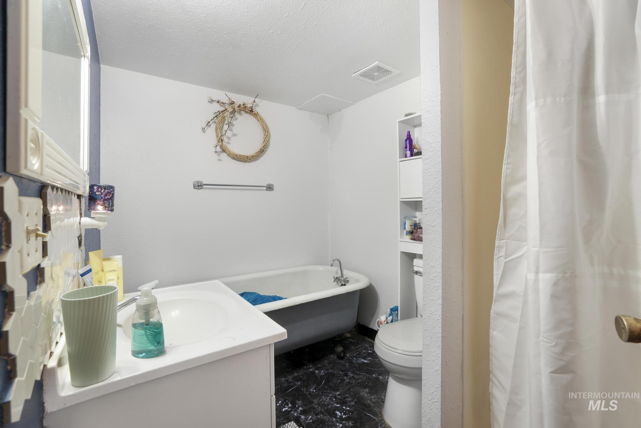242 8th Avenue East Twin Falls, ID 83301 - Photo 26 of 35 Full bathroom with a freestanding tub, vanity, a textured ceiling, and a shower with shower curtain